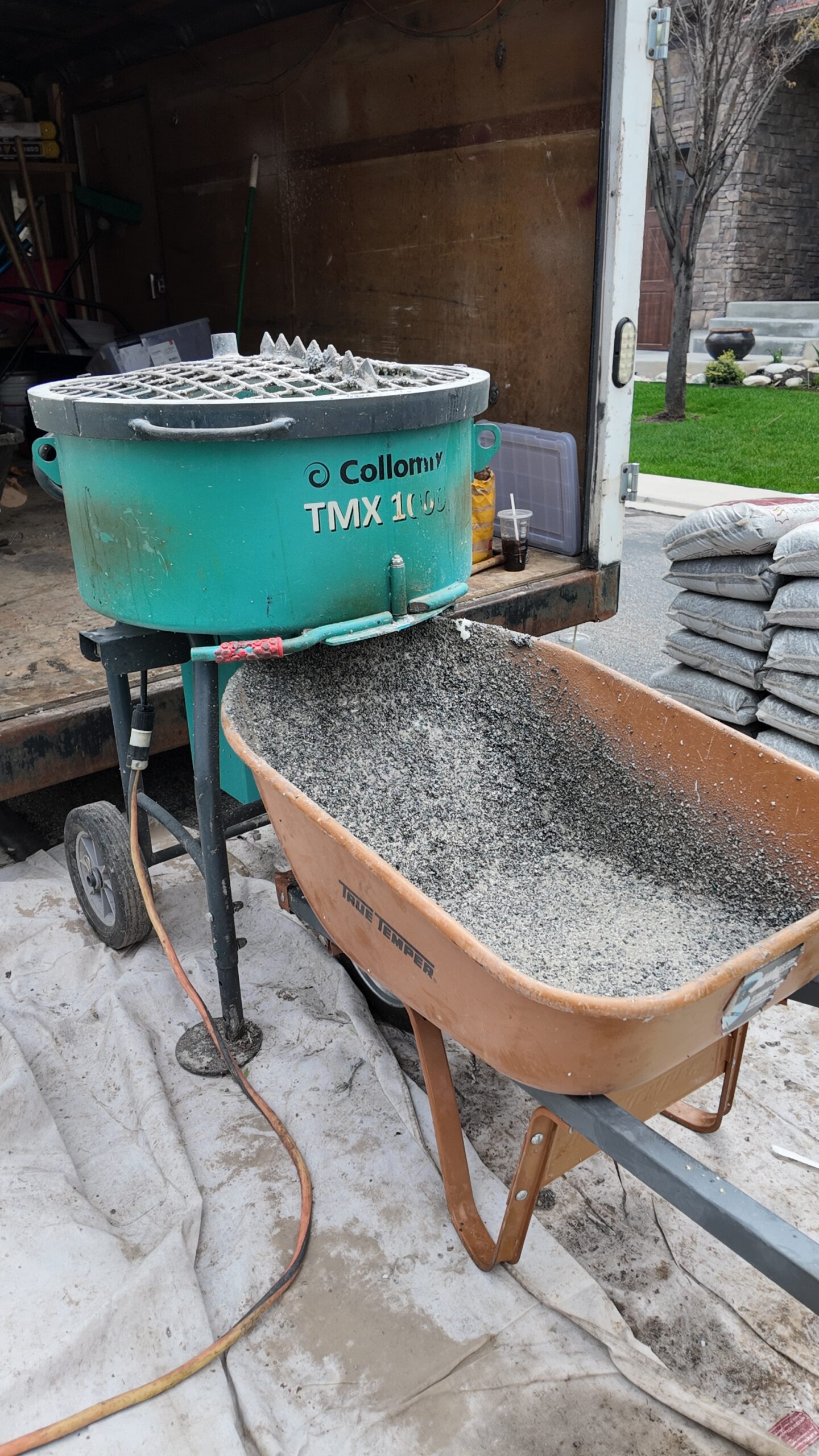 A wheelbarrow full of Vuba stone is next to a mixer full of Vuba stone and epoxy, getting ready to coat a concrete patio in Gillette, UT, by the team at Based On Concrete LLC